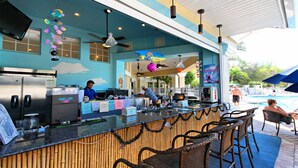 A bar area with a counter, seating, and a poolside view.