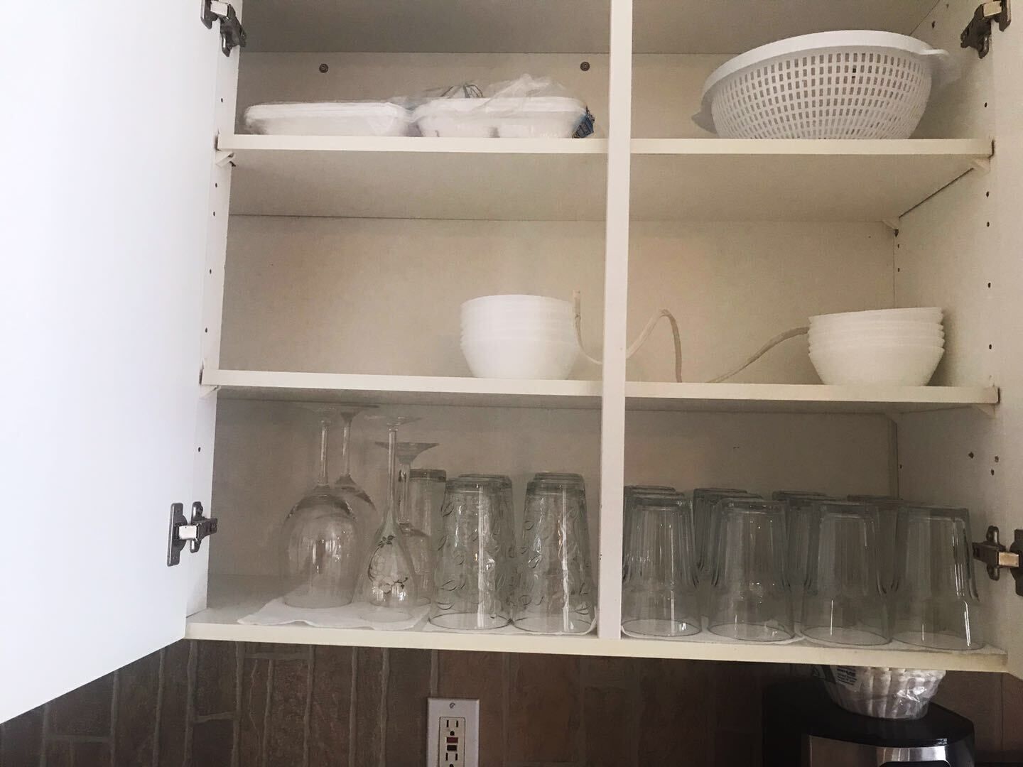 Ein Küchenschrank mit Regalen, der verschiedene Gläser und Schüsseln beherbergt.