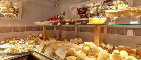 A buffet with various food items including bread, fruits, and desserts.