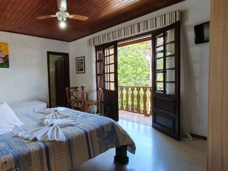 Un dormitorio con cama, ventilador de techo, un cuadro, una puerta y un balcón.