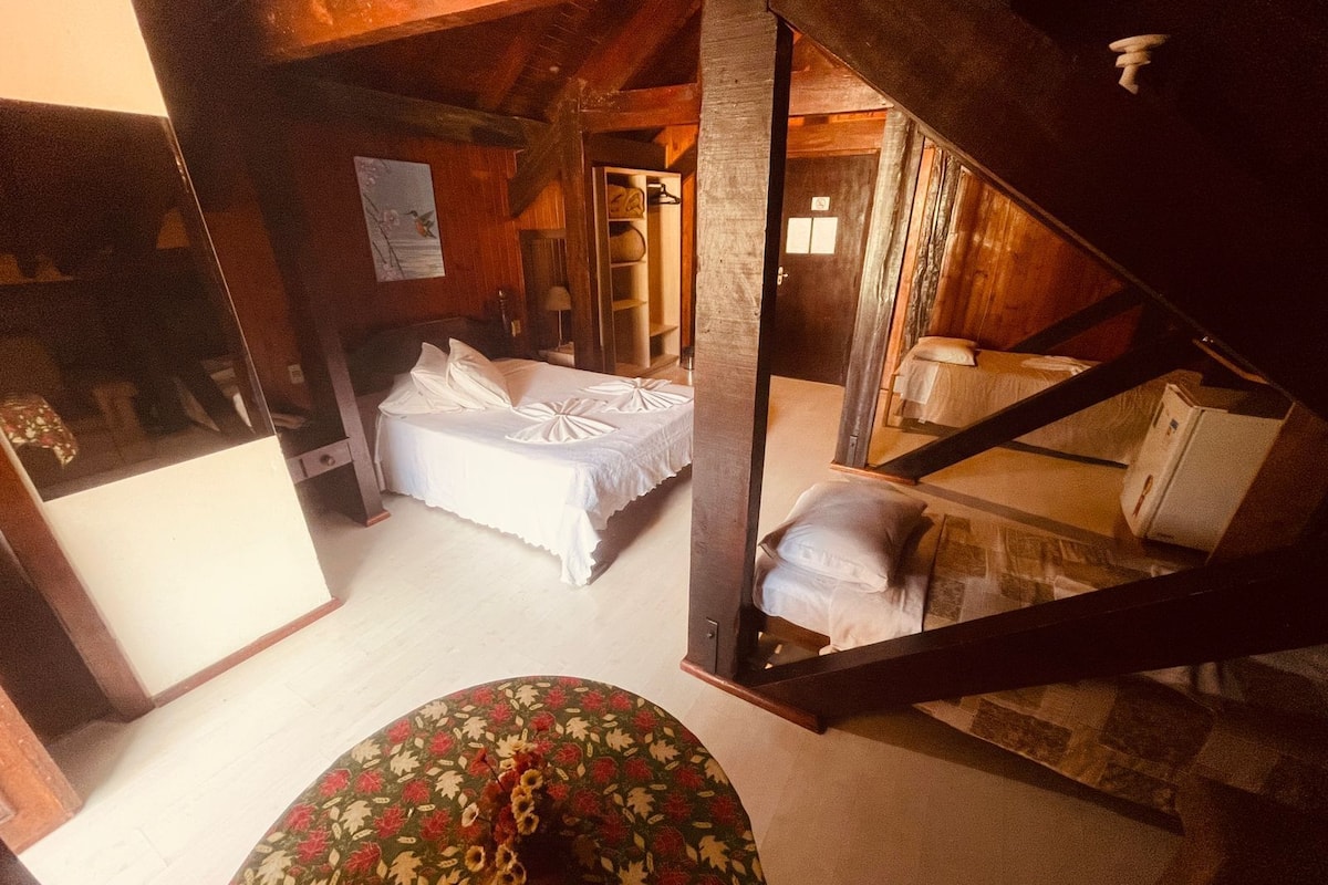 Um quarto rústico de madeira com uma cama, uma mesa pequena e uma cadeira.