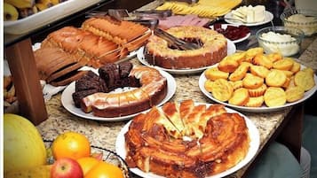 Un bufé con diversas opciones de comida, incluyendo pan, pasteles y frutas.