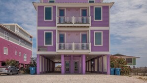 A two-story building with a balcony on the second floor, a covered entrance, and a parking area in front.