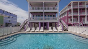 A two-story building with a pool area, including a staircase and lounge chairs.
