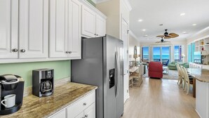 A modern kitchen with white cabinets, a stainless steel refrigerator, and a coffee maker on the counter.
