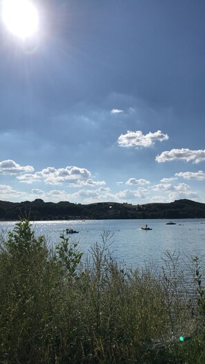 Ein Gewässer mit Booten, einem klaren Himmel und sanften Hügeln in der Ferne.