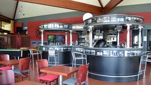 A bar area with a pool table, multiple seating arrangements, and a counter with a bartender.