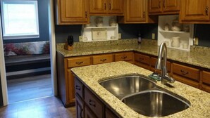 Una cocina con armarios de madera, encimeras de granito y un lavamanos de acero inoxidable.