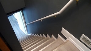 Una escalera con peldaños de madera y barandillas blancas, que conduce a una pared oscura.