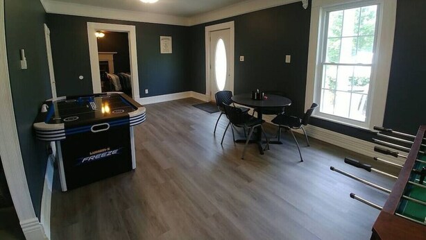Una habitación con mesa de billar, mesa de futbolín y una mesa de comedor con sillas.
