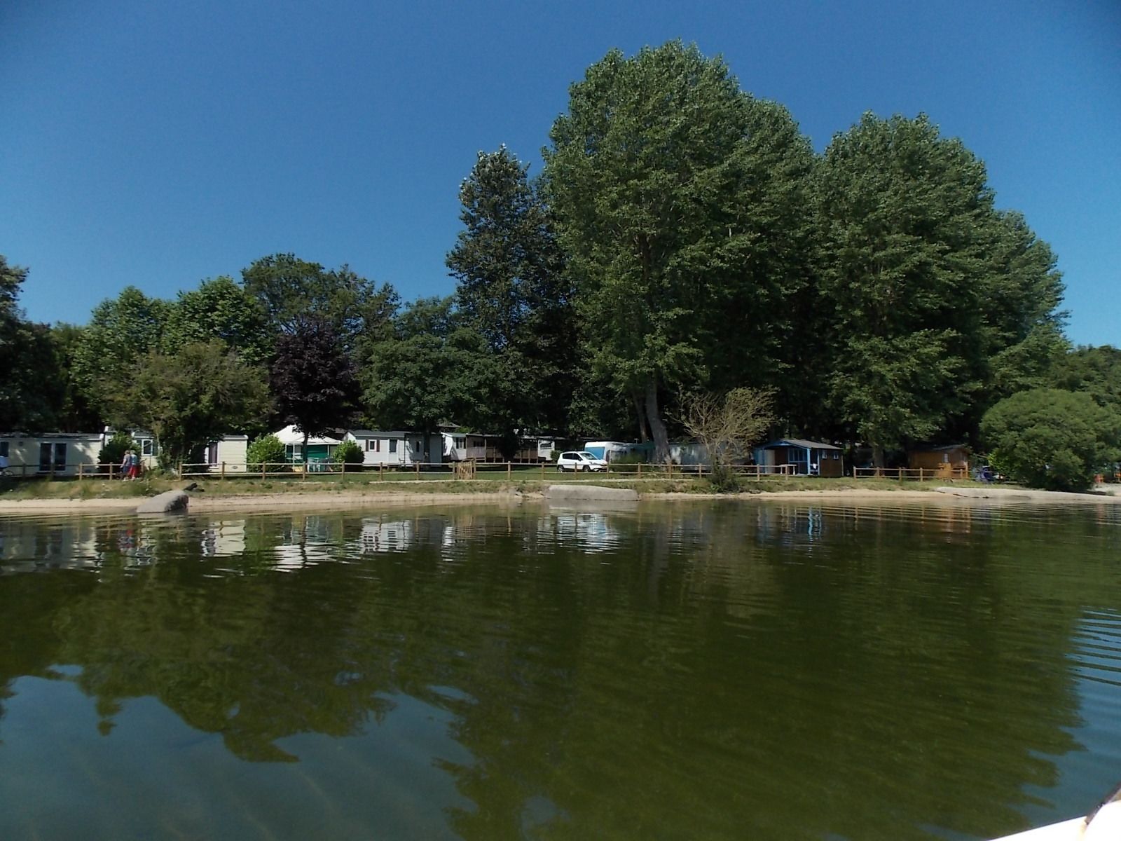 A lakeside view with several mobile homes and a small dock.