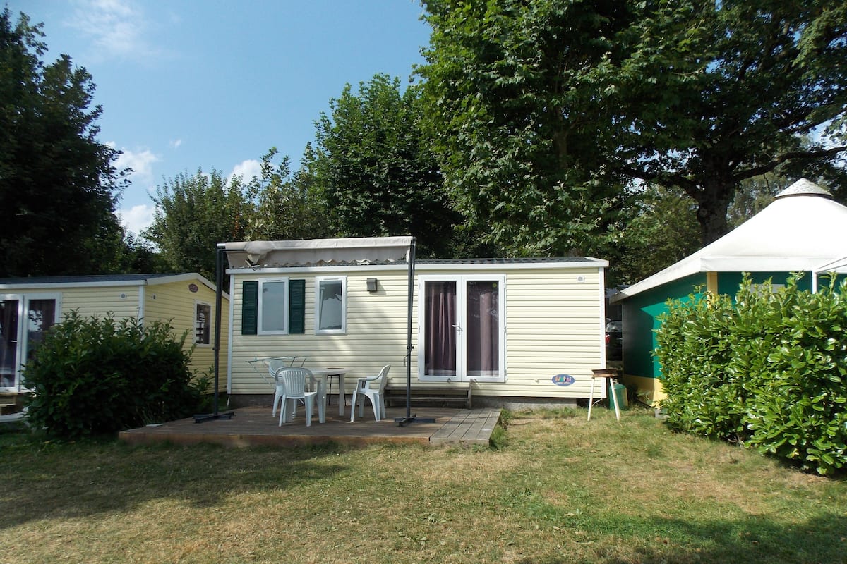 A mobile home with a patio area, a small table, and two chairs.