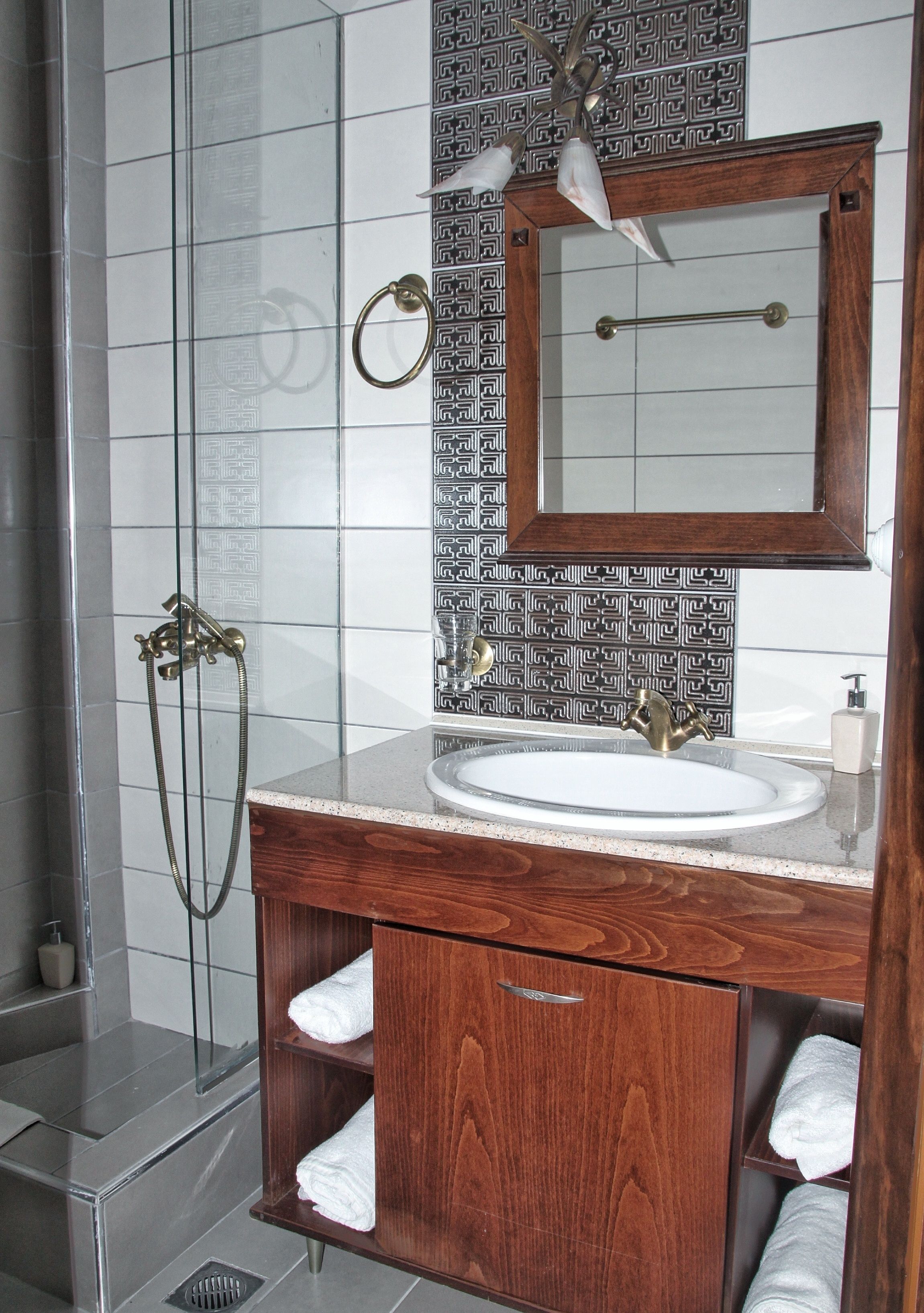 A bathroom with a glass-enclosed shower, a wooden vanity with a sink, and a mirror above it.