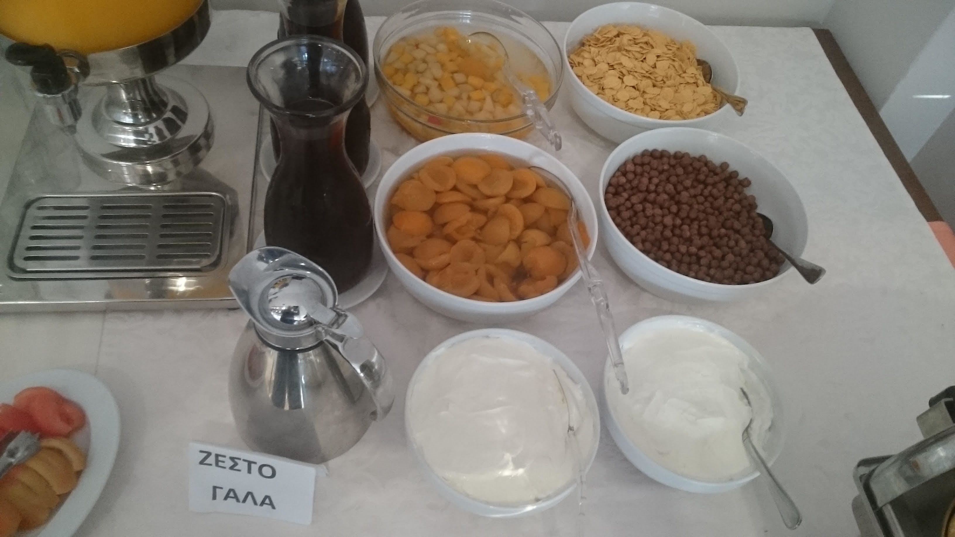 Una mesa con diversos alimentos, entre ellos tazones de frutas, nueces y una jarra con la etiqueta 'ZEZTOS GALA'.