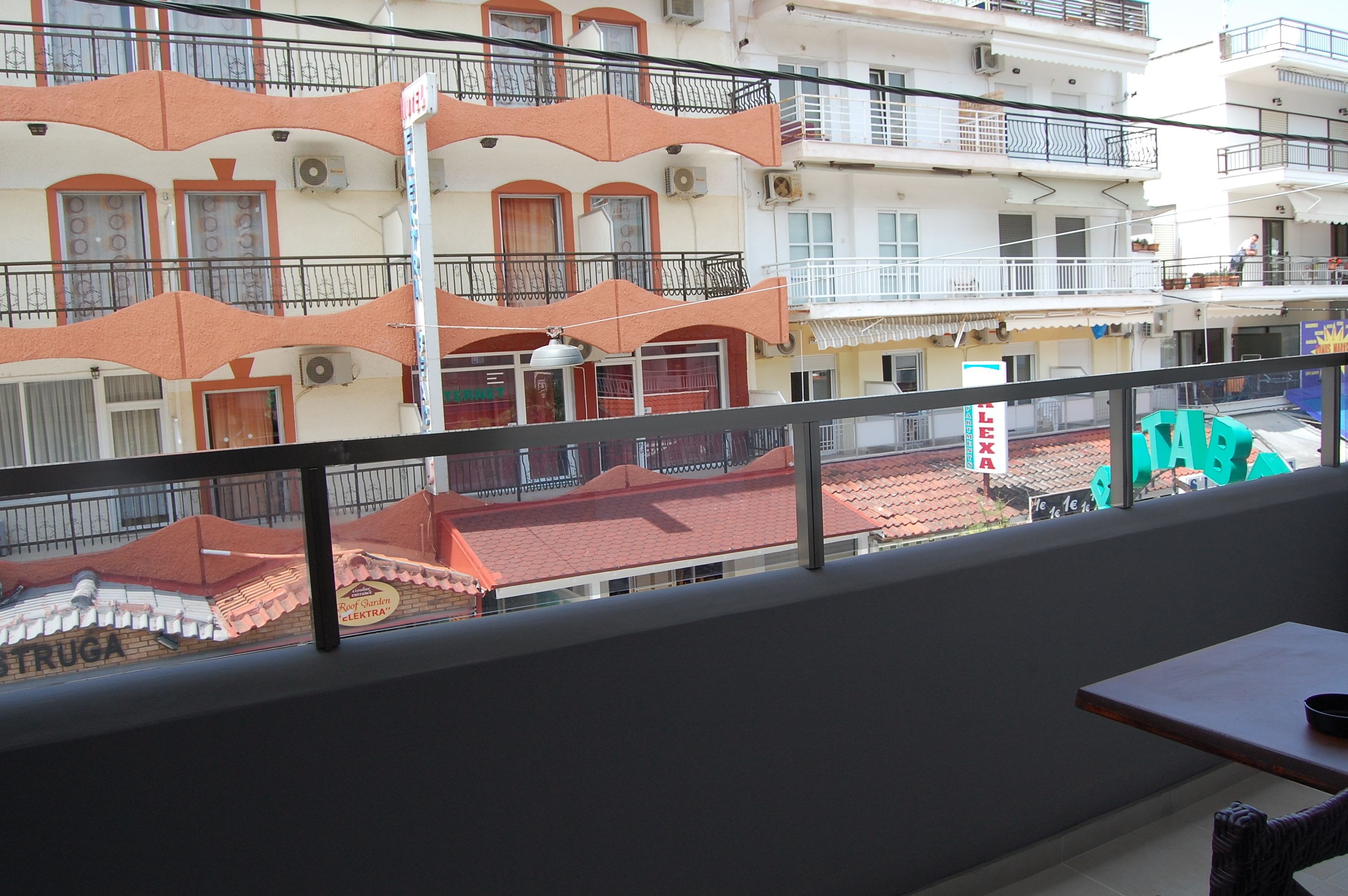 Een balkon met uitzicht op een gebouw met balkons, airconditioning en een bord waarop 'LETRA' staat.
