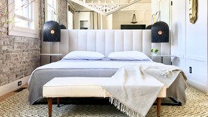 A modern bedroom with a large bed, a bench, and a unique ceiling design. - Luxuriously Restored Loft in Old Town Alexandria (Alexandria)