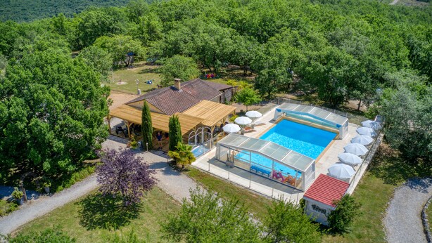 En vy över en fastighet, tagen från luften, som visar en swimmingpool, ett takförsett utomhusområde med sittplatser och en liten byggnad.