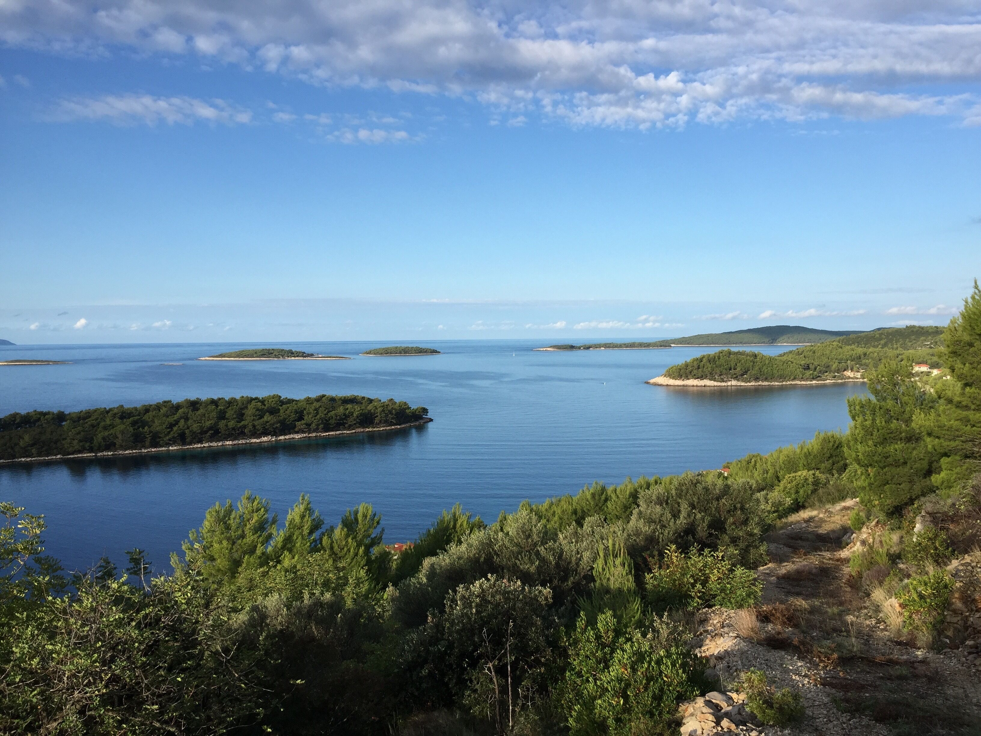 Eine Küstenlandschaft mit freiem Blick auf das Meer, mehreren kleinen Inseln und dichter Vegetation.