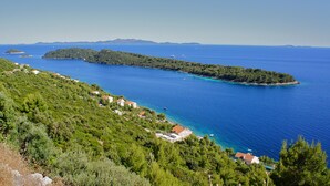 Un paysage côtier avec une petite île, une mer d’un bleu limpide et une végétation luxuriante.