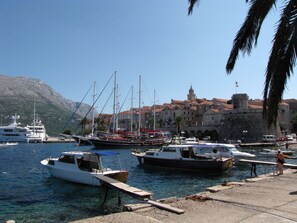 Un puerto deportivo con barcos amarrados, un edificio histórico con torre y agua cristalina.