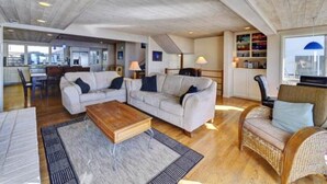 A spacious living area with a high ceiling, a sofa set, a coffee table, and a wicker chair. - Luxury Ocean Front Home (Aptos)