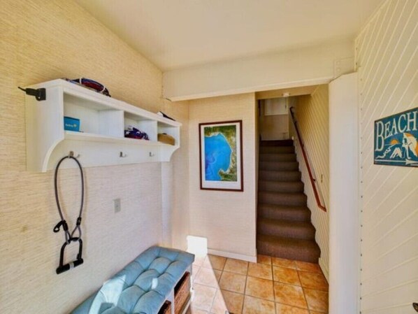Une pièce comprenant un lit, une petite table, une étagère avec divers objets, un tableau encadré et un escalier menant à un autre espace.