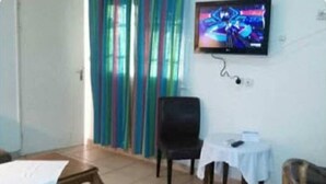 Ett rum med en säng, en stol, ett litet bord och en tv på väggen.