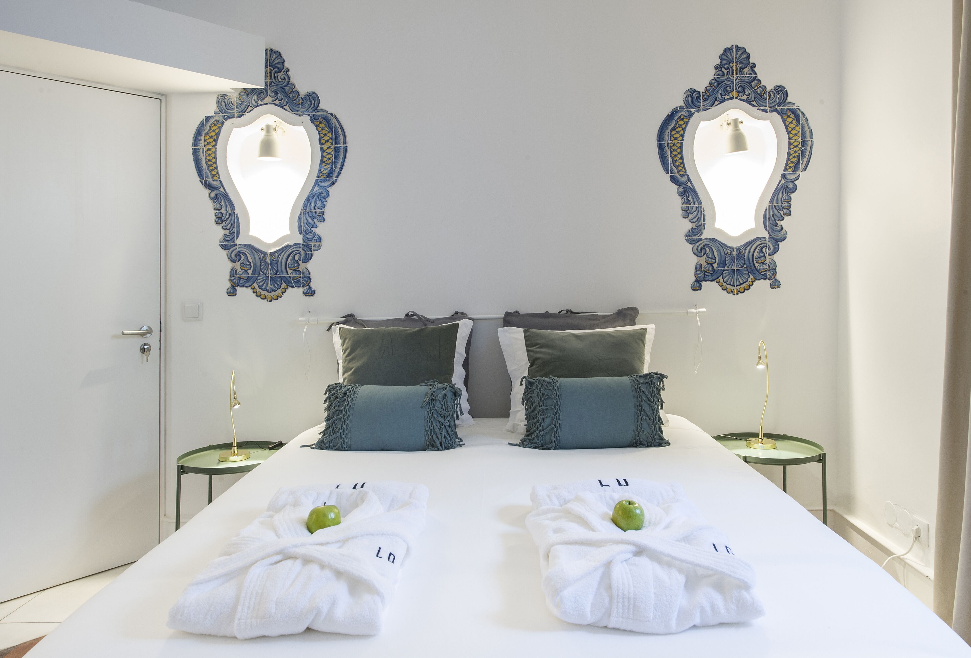 A hotel room with a large bed, two nightstands, decorative mirrors, and a door.