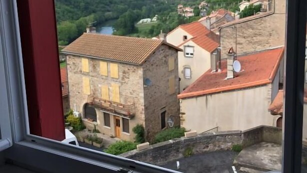 A view from a window overlooking a town with stone buildings and a river. - Auberge de Saint Rome (Saint-Rome-de-Tarn)