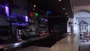 A bar area with a long counter, shelves with bottles, and a decorative structure in the background. - Auberge de Saint Rome (Saint-Rome-de-Tarn)