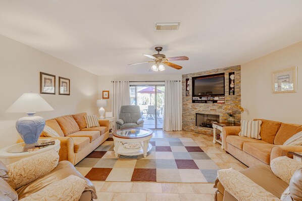 A living room with a checkered floor, two sofas, a coffee table, a TV, and a fireplace.