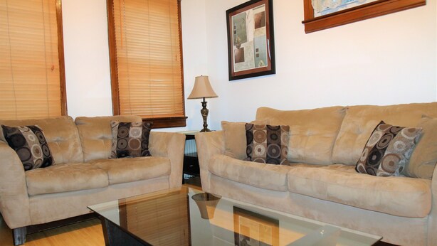 A living room with two beige sofas, a glass coffee table, a lamp, and a framed picture on the wall. - Spacious 1br Apartment in Raritan- Fully Furnished!  (Raritan)