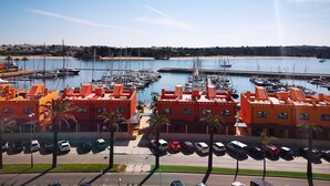 Un port de plaisance avec des bateaux, un parking et des bâtiments aux façades orange.