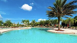 Une piscine à l’eau d’un bleu cristallin, entourée de palmiers et de chaises longues.