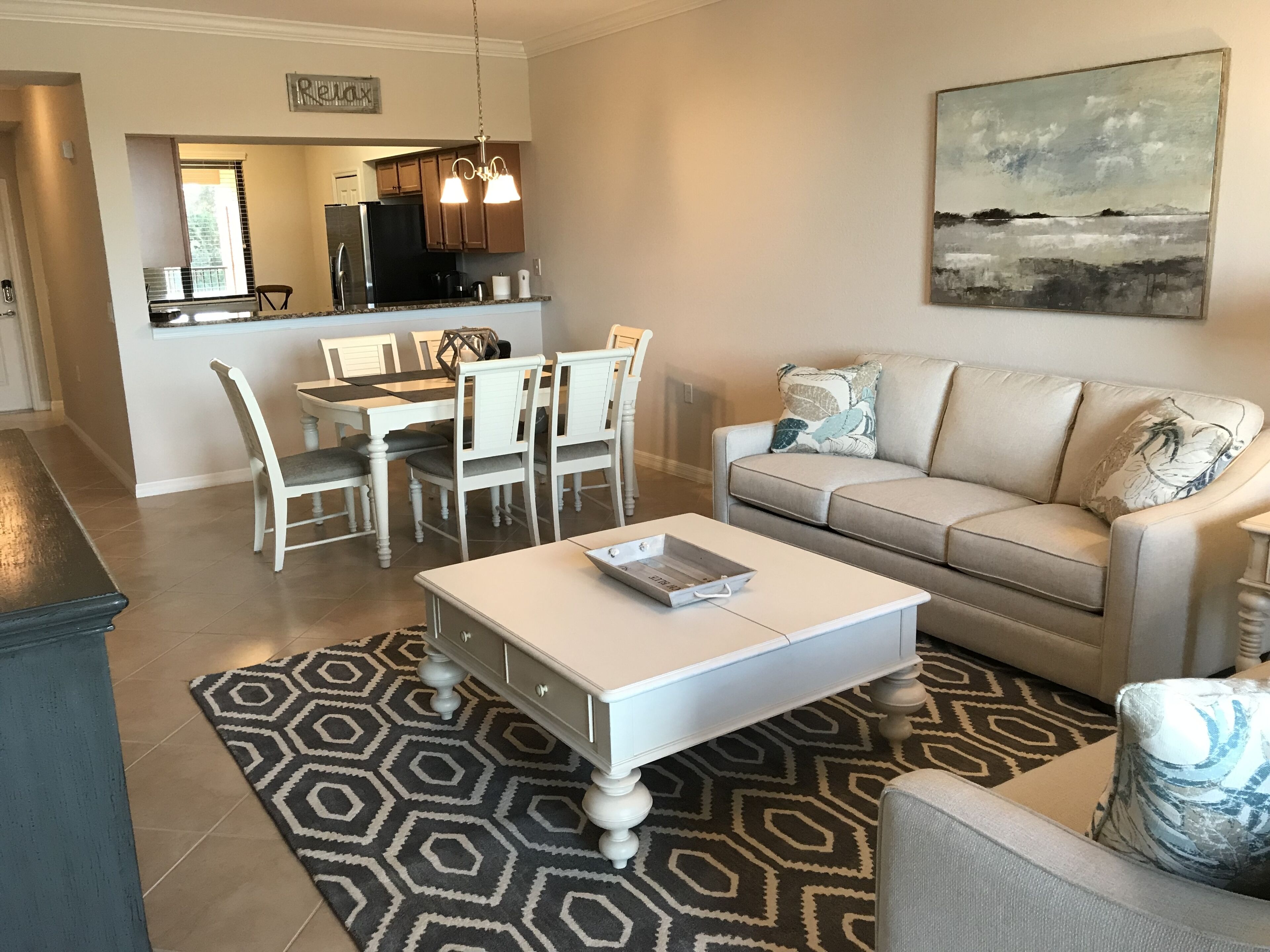 Un salon avec un canapé blanc, une table basse et un coin repas comprenant une table et des chaises.