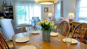 Un coin repas avec une table en bois dressée pour quatre personnes, entourée de chaises en bois.