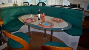 A cozy dining area with a round table, teal cushioned seating, and a small stage with musical instruments. - Dreamcatcher (Cole Bay)