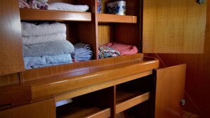 A wooden closet with shelves holding folded towels and a canister. - Dreamcatcher (Cole Bay)