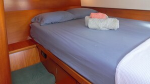 A compact cabin with a single bed, a small bench, and a control panel on the wall. - Dreamcatcher (Cole Bay)