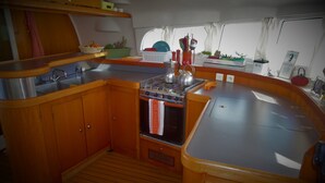 A compact kitchen with wooden cabinets, a stainless steel sink, and a stove. - Dreamcatcher (Cole Bay)