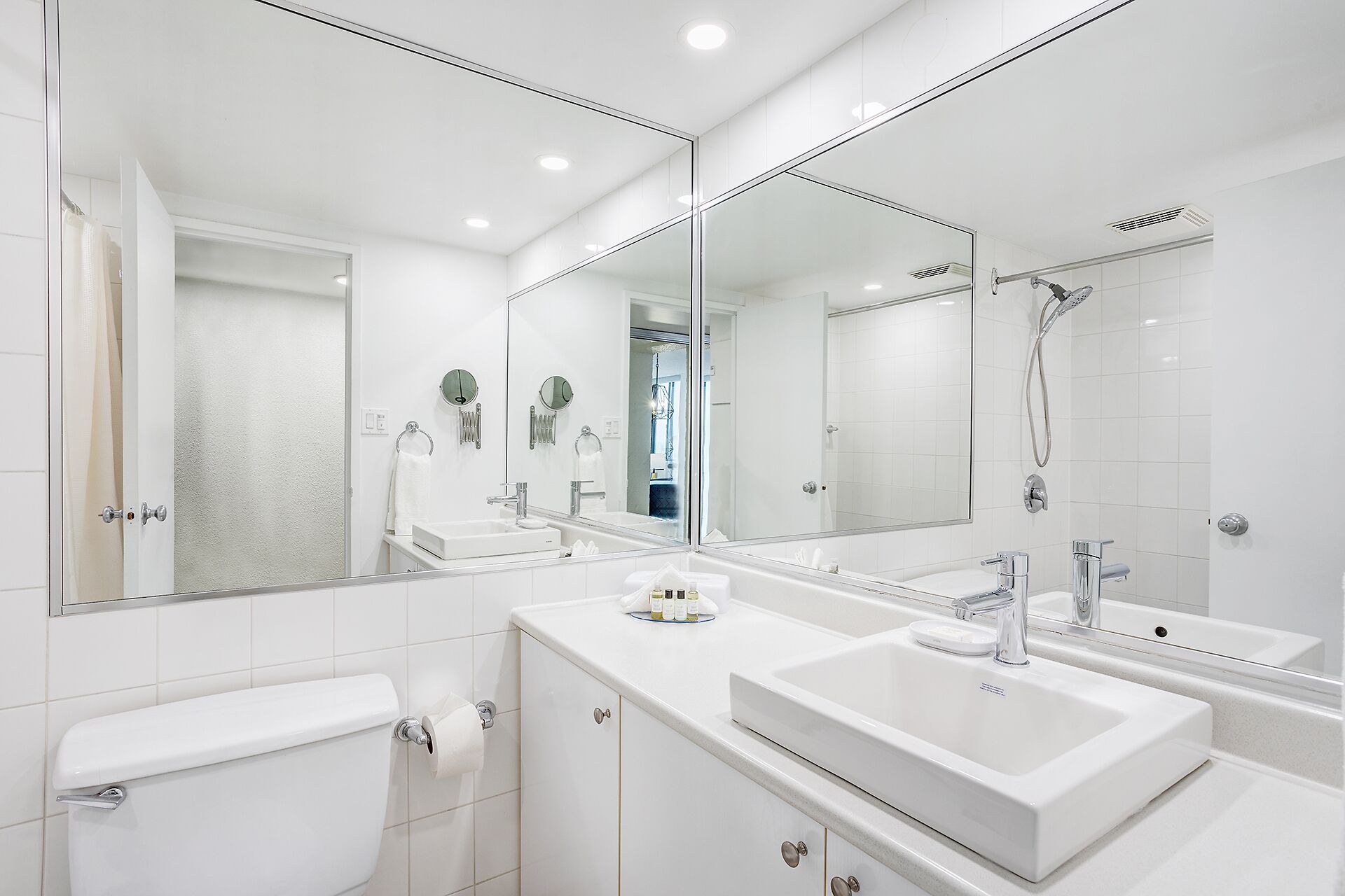 A modern bathroom with two sinks, a toilet, and a shower.