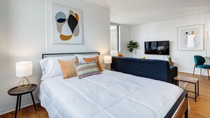 Een moderne hotelkamer met een groot bed, nachtkastjes, een televisie en kunstwerken aan de wanden.