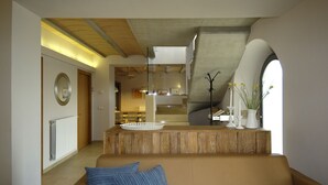 Ein Wohnzimmer mit einem beigen Sofa, einem Holztisch und Blick zur Küche durch einen Bogen.