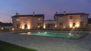 Ein zweistöckiges Steinhaus mit einem Pool davor.