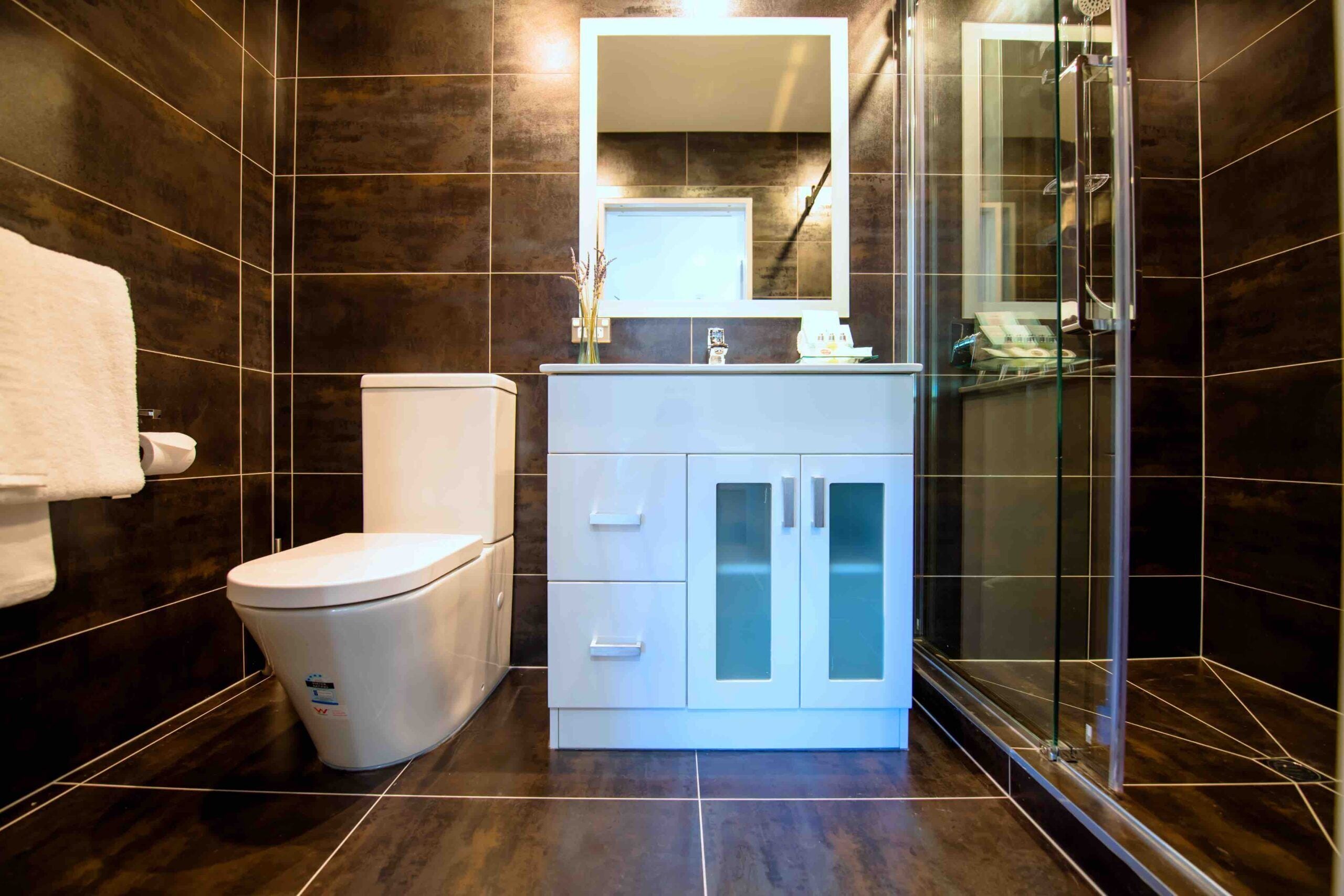 A modern bathroom with a toilet, vanity, and shower.