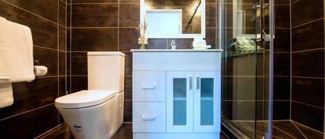 Un baño moderno con inodoro, tocador y ducha.