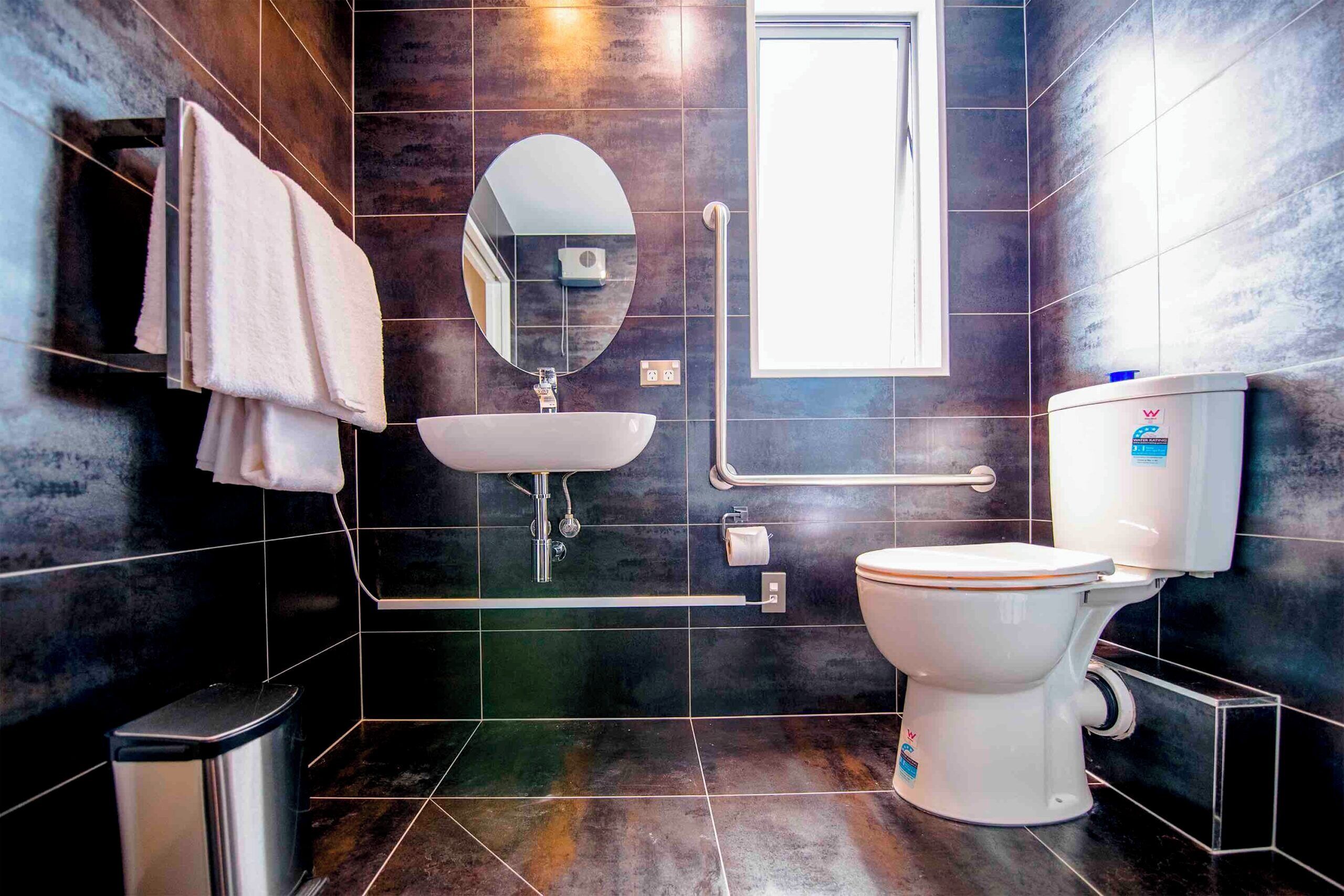 A modern bathroom with a toilet, sink, and mirror.