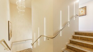 A staircase with a handrail, a chandelier, and a framed picture on the wall. - Alpine Hotel (Christchurch)