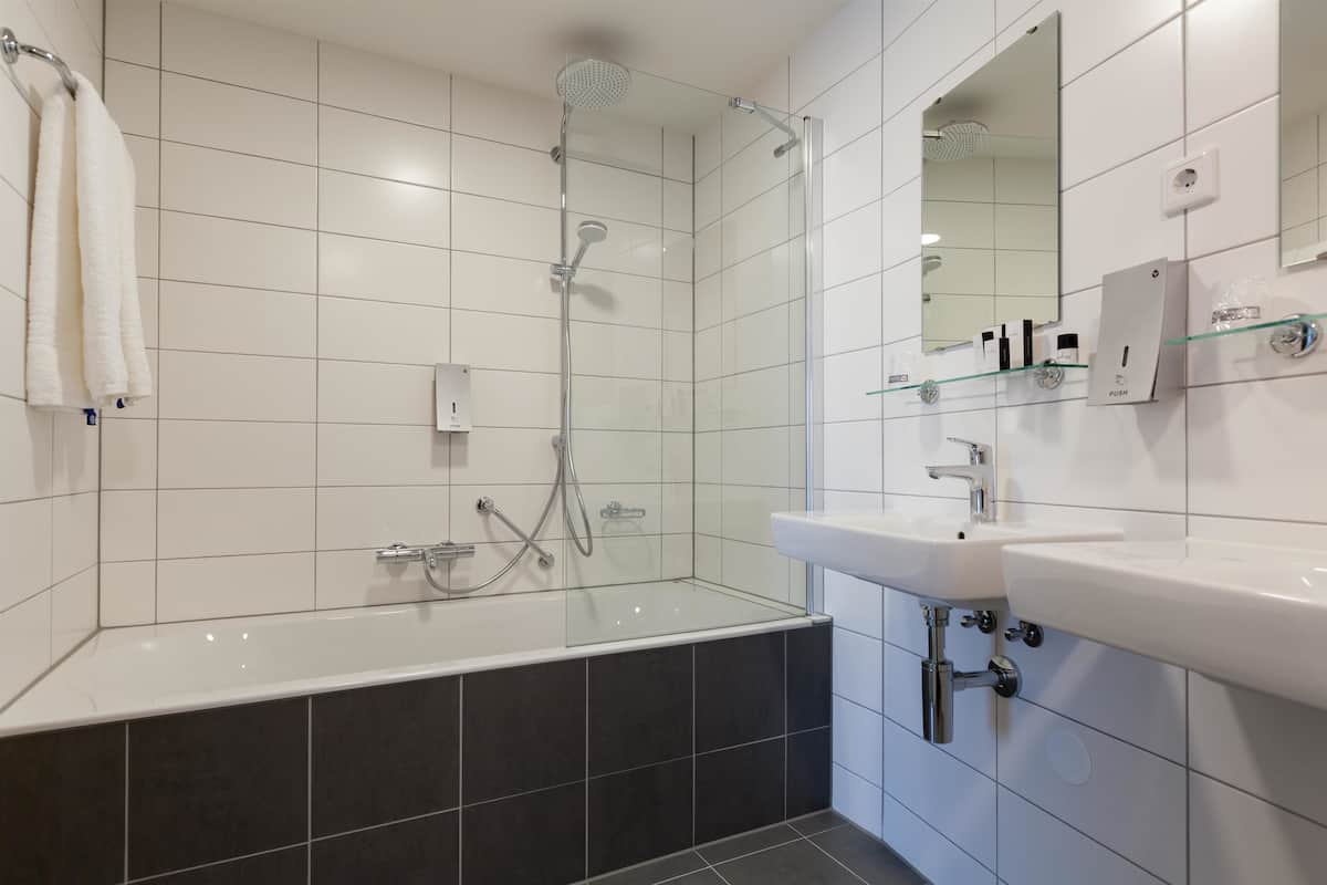 Un bagno moderno con doccia vetrata, lavandino bianco e un ampio specchio.