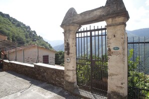 A stone gate with a metal fence, a stone wall, and a building with a red door. - Holiday Home in Stazzema with 2 bedrooms sleeps 5 (Stazzema)